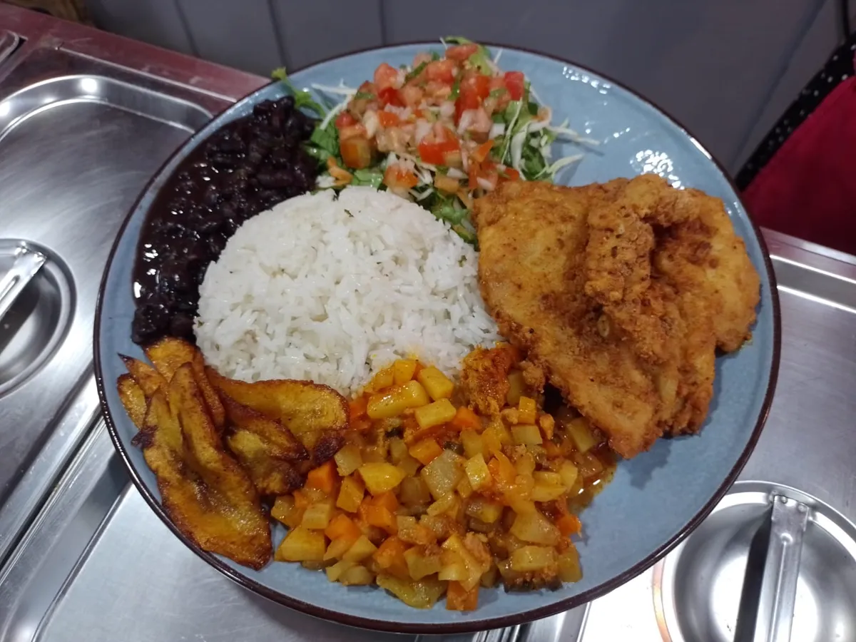 Casado con filete empanizado, arroz, frijoles negros, plátano frito, guiso de papa y zanahoria, y ensalada fresca, en un plato azul